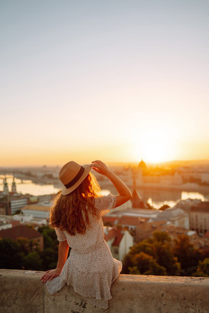 Young female tourist enjoys view of the city at sunset. back view Lifestyle, travel, nature, active lifeの写真素材