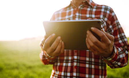 Tablet in the hands of a farmer. Smart farm. Farmer checking his crops on an agricultural field..の写真素材