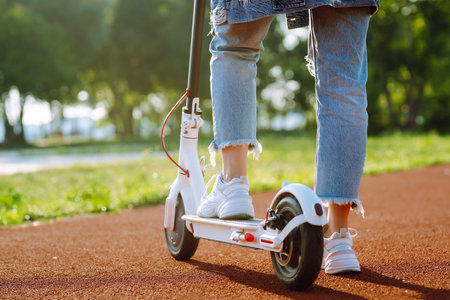 Women's legs on electric scooter outdoors. Electric vehicles. Ecological transport. Active lifestyleの写真素材