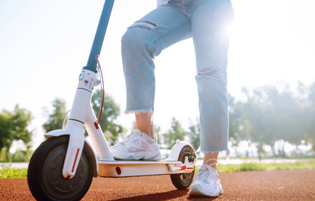 Women's legs on electric scooter outdoors. Electric vehicles. Ecological transport. Active lifestyle