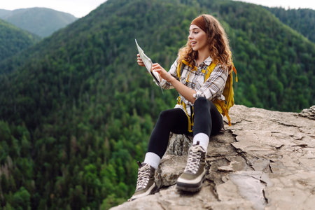 Traveler with yellow backpack and map in hands on a cliff in the mountains. Adventure concept.の写真素材