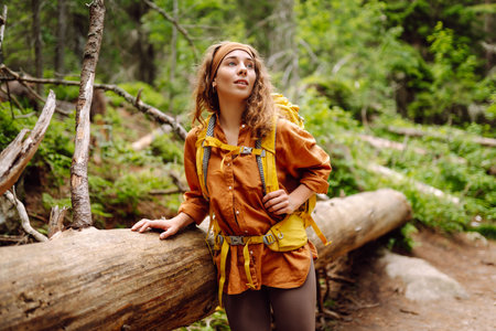 Smiling woman traveler along a forest hiking trail in the mountains against the backdrop of nature.の写真素材