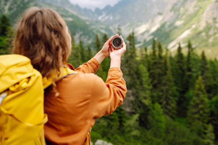 Wanderlust concept. Stylish woman holding a compass in her hand while traveling in the mountains.の写真素材