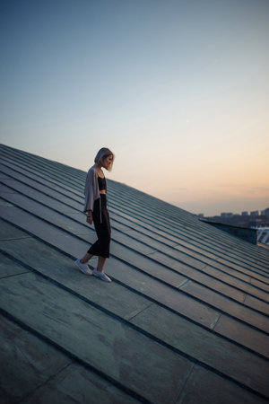 Photo shoot on roof. Young woman posing in roof at sunset. People, lifestyle, relaxation concept.の写真素材
