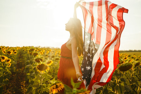 Beautiful girl in hat with the American flag in a sunflower field. 4th of July. Fourth of July....