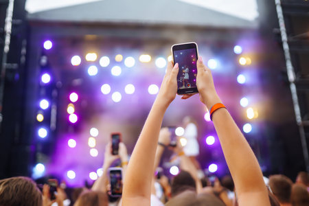 Hand with a phone records live music festival. People taking photographs with smart phone.の写真素材