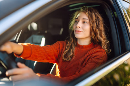Young smiling woman driving a car drives around the city. Lifestyle concept.の写真素材