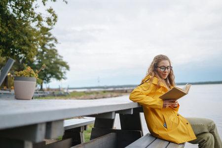 Young woman reading a book in the park. Relaxation, enjoying, solitude with nature.の写真素材