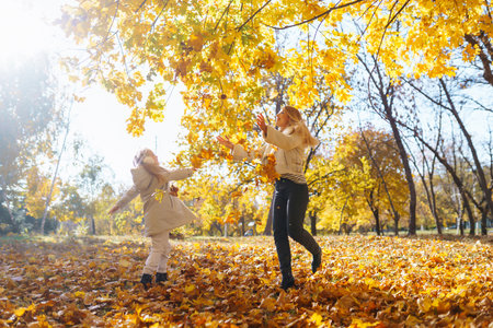 Stylish mother and daughter enjoy the autumn park.