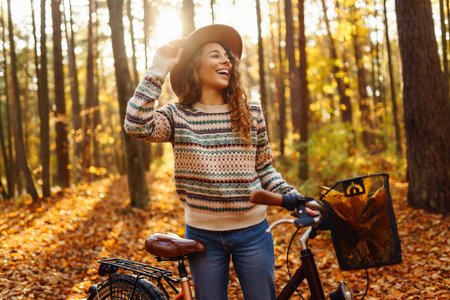 Happy active young woman on bike in autumn park at sunset. Concept of people, recreation, active lifestyle.の写真素材