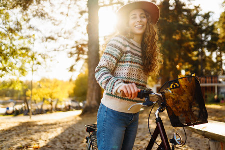 Happy active young woman on bike in autumn park at sunset. Concept of people, recreation, active lifestyle.の写真素材