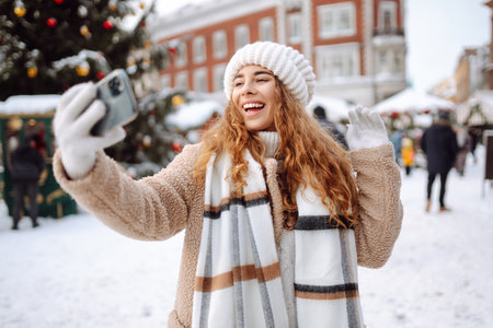 Happy woman drinking hot drink and taking selfie on winter snowy day. Weekend concept.の写真素材