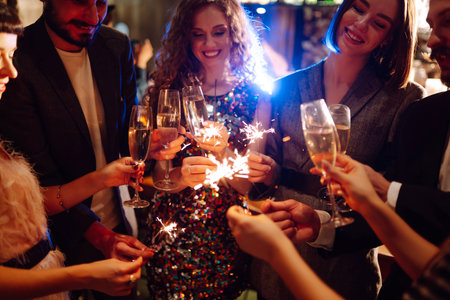 Glowing sparkles in hands. Group of happy people enjoying party with fireworks. Winter holiday.の写真素材