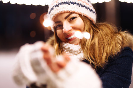 Cheerful young woman holding a sparkler in hand in forest. Woman happiness and playing firework.の写真素材