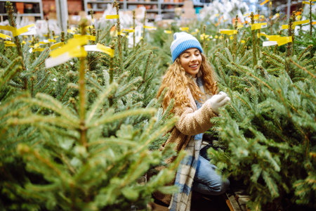 young smiling woman chooses Christmas tree to buy. Happy woman buying New Year tree for Christmas.の写真素材