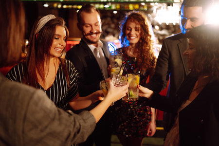 Cheering and drinking cocktails. Group of friends partying in nightclub, toasting drinks cocktails.