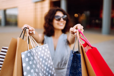 Shopping time. Young woman with shopping bags near the mall. Consumerism, sales, purchases.の写真素材