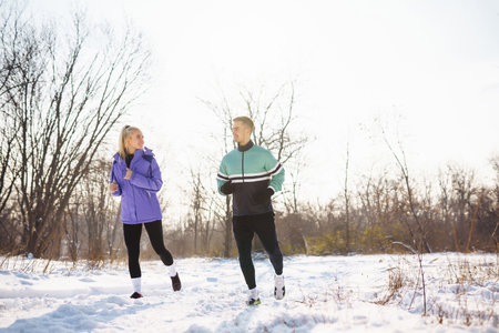 Young couple in sportswear doing morning exercise at snowy forest. Healthy lifestyle concept.の写真素材