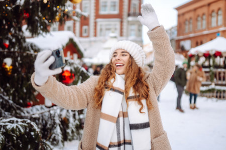 Young tourist uses a smartphone while walking through a Christmas market.の写真素材
