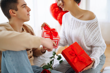Young couple at home celebrating Valentine's Day. Exchange of gifts. Surprise and love concept.の写真素材