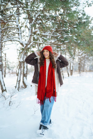 Beautiful Young Smiling woman in her Winter Warm Clothing walking in the snow forest.の写真素材
