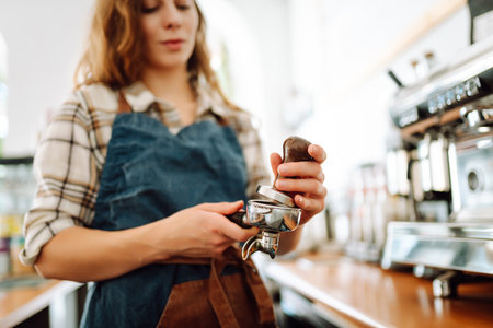 Woman bartender prepares a drink using a coffee machine in a cafe. Takeaway food.の写真素材