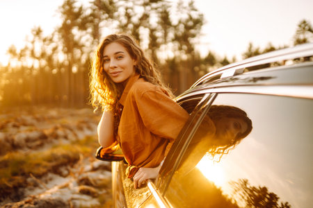 Shot of an attractive woman leaning out of car window while driving. Active lifestyle, travel.の写真素材