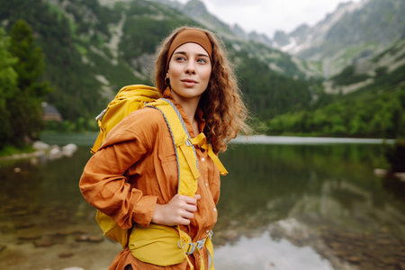 Travel Slovakia, Europe. Tourist with a yellow backpack stands against the backdrop of alpine lake.の写真素材