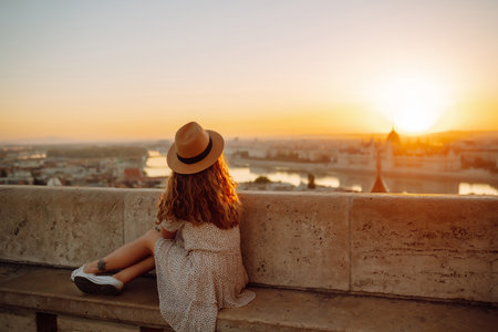 Young female tourist looking at panoramic view of the city at sunset. Lifestyle, travel, active lifeの写真素材