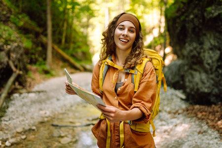 Young woman on a mountain path with a map in her hands, exploring hiking trails. Adventure concept.