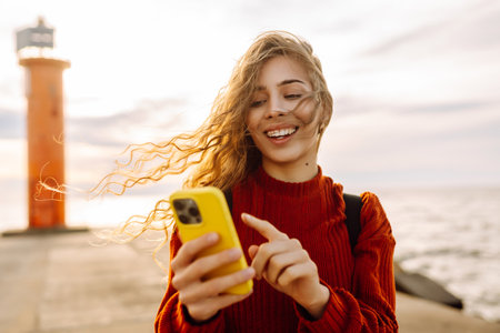 Young woman enjoying nature by the waterfront during a cloudy day by a lighthouse. Blogging conceptの写真素材