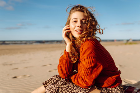 Portrait of curly woman on beach in cold sunny weather. Travel, weekend, relax and lifestyle conceptの写真素材