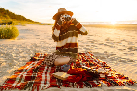 Woman photographer takes pictures on vacation on retro camera in picnic at beach. Blogging concept.の写真素材