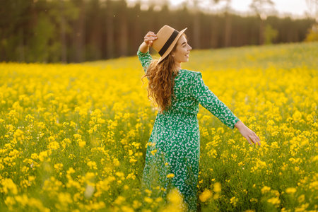 Young woman walking flowering field gently touch yellow flowers. Summer landscape.の写真素材