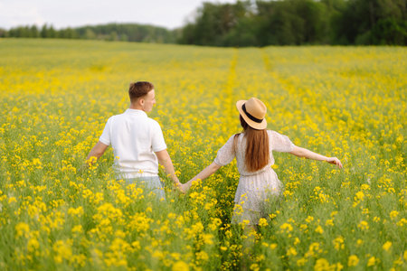 Young couple in love walks through a rapeseed field.の写真素材