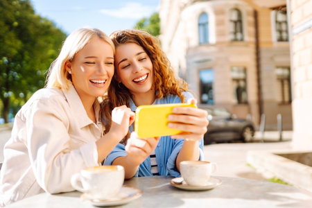 Young women enjoying in coffee and having fun with smartphone. Coffee break after shopping.の写真素材