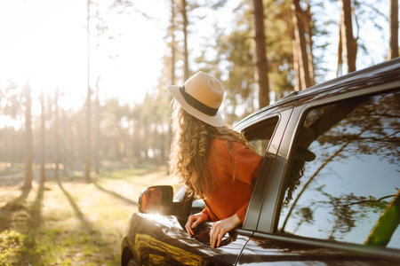 Young woman leaning out of the car window enjoying nature. Road trips summer holidays.の写真素材