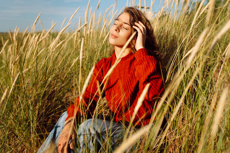 Beauty woman enjoying nature outdoors in grass. Calmness and tranquility. Travel, tourism concept.の写真素材
