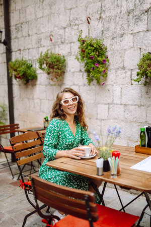 Young woman tourist drinks coffee in the old town in summer trip. People, fashion, lifestyleの写真素材