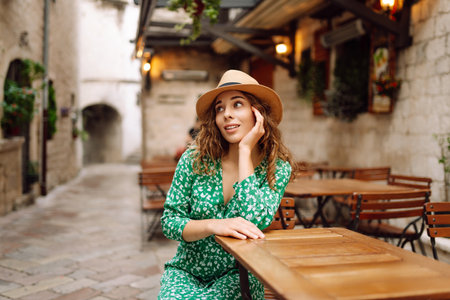 Young woman sitting by table of outdoor sidewalk cafe restaurant. People, fashion, lifestyleの写真素材