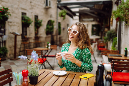 Young woman tourist drinks coffee in the old town in summer trip. People, fashion, lifestyleの写真素材
