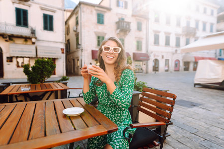 Young woman enjoying coffee at a cozy outdoor cafの写真素材