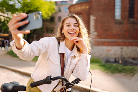 Woman using mobile phone while walking with a bicycle. Selfie time. People, blogging and lifestyle.の写真素材