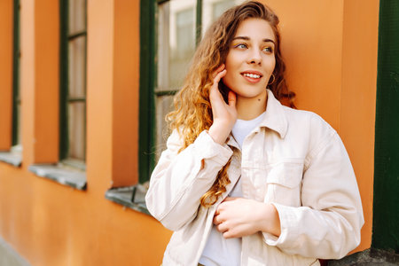 Optimistic woman with curly hair walking on the street city. Concept of lifestyle, fashion, travel.の写真素材