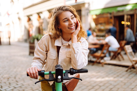 Happy woman rides an electric scooter in the city street on a sunny day. Ecological transport.の写真素材