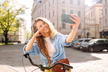 Woman using mobile phone while walking with a bicycle. Selfie time. People, blogging and lifestyle.の写真素材