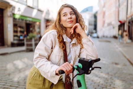 Happy woman rides an electric scooter in the city street on a sunny day. Ecological transport.の写真素材