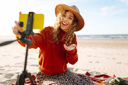 Happy woman using smartphone with stabilizer, live video in on sea beach. Live session blogging.の写真素材