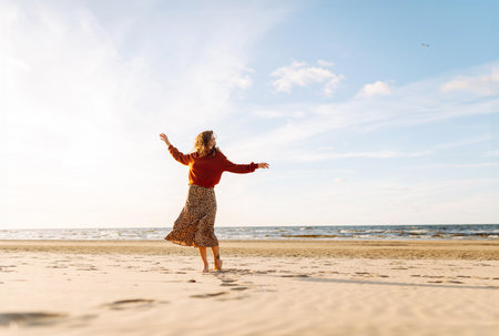 Stylish woman walks at sunset along beach of sea on at sunset. Travel, relax and lifestyle concept.の写真素材
