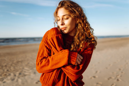 Portrait of curly woman on beach in cold sunny weather. Travel, weekend, relax and lifestyle conceptの写真素材